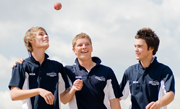 three sport students tossing cricket ball