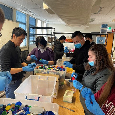 A group or people sort through plastic lids