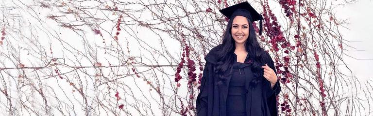 Female student in graduation gown looking proud