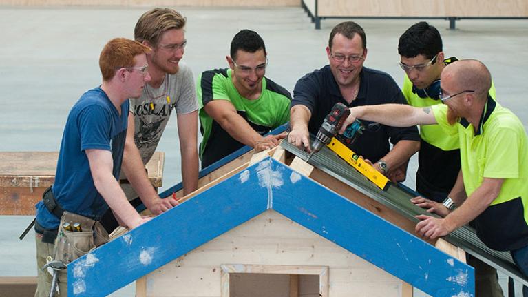 Construction students at Sunshine Construction Hub making a dog house.