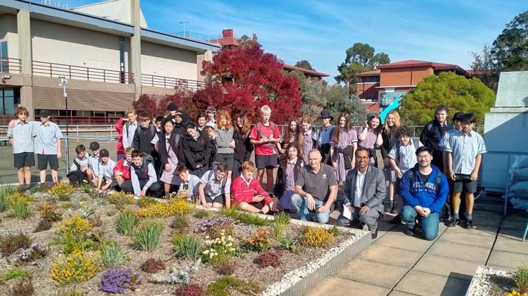 A group of school kids and adults near a rooftop garden