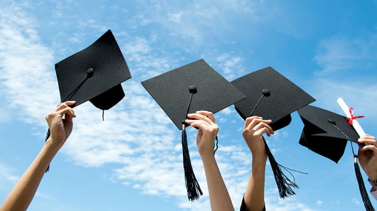 Students throwing graduation hats into the air.