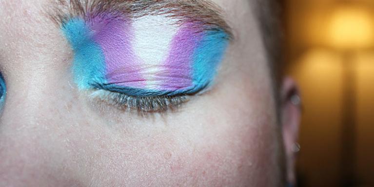 It is important not to judge another by their gender identity or deny that it exists.  People with the colours of the transgender flag on their eyelid.