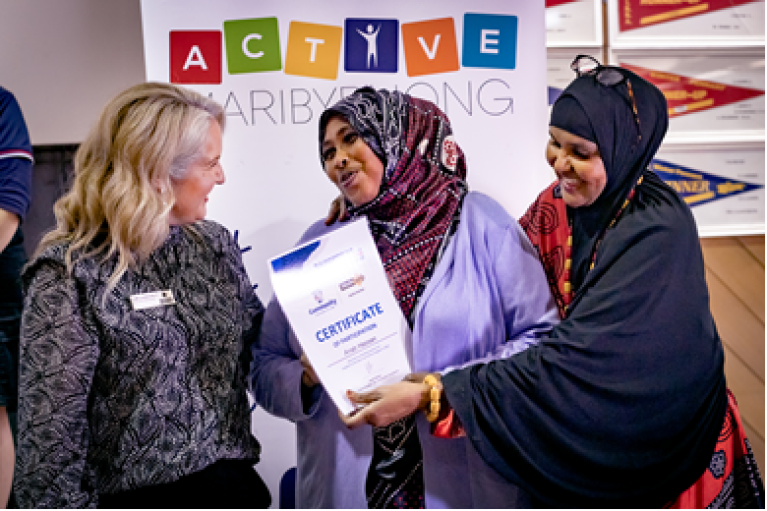 Two women in hijab laugh as they accept an award