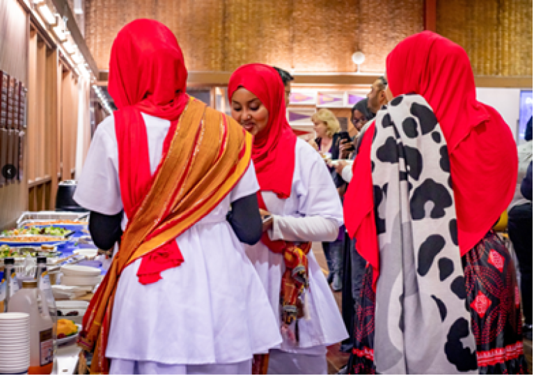 3 women in bright hijab in smile and chat in a communal eating space