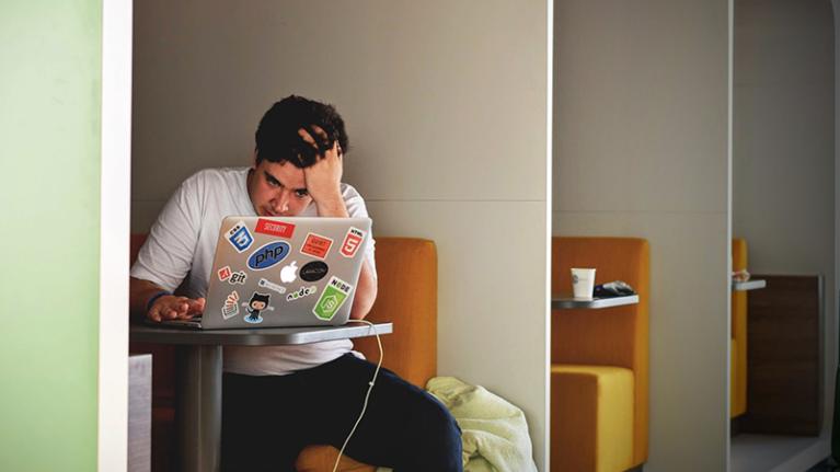  young man looking anxious in front of laptop