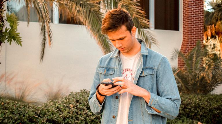  boy walking down street looking at smartphone