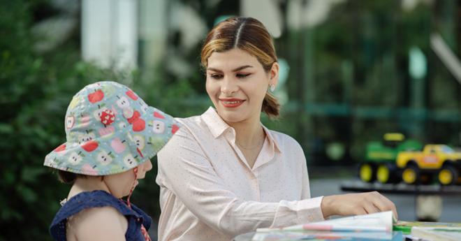 Early childhood teaching student smiles at kindergarten child
