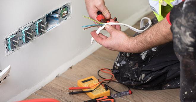 An electrician fixes a power point