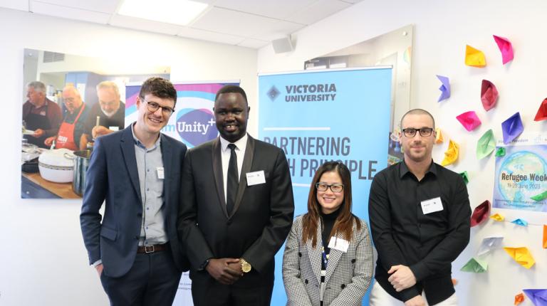 Four people standing in front of a VU and commUnity+ sign - smiling at camera.