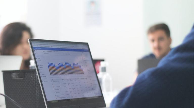 Three people sitting around a computer with data and graphs on the screen