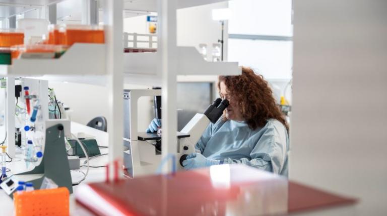 Vasso Apostolopoulos in a lab, looking through a microscope