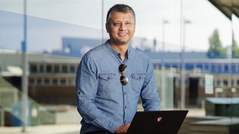 Man with computer, professionally dressed, smiling at camera