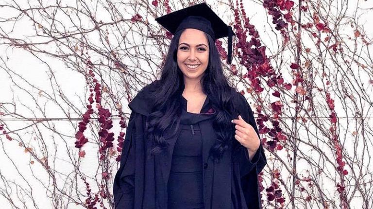 Female student in graduation gown looking proud