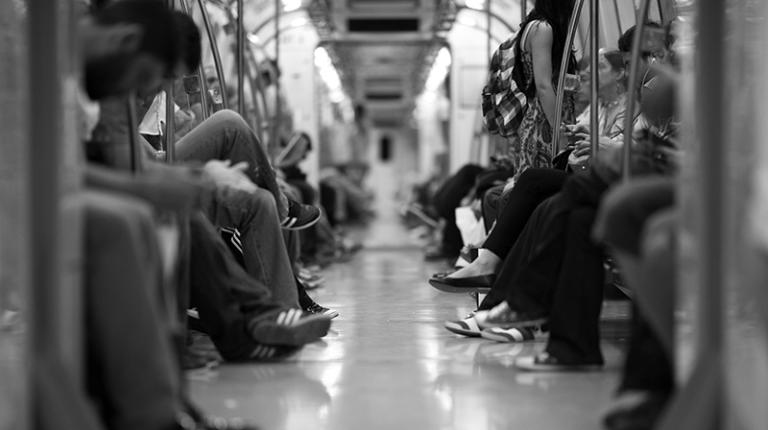 train showing passenger legs and a woman facing away with a backpack 