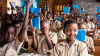 Group of Afrtican school children, in class, wearing uniforms, smiling and holding books