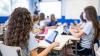  Primary school kids sitting as desks with tablets in a classroom.