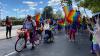 A group on bikes and on foot waving rainbow flags