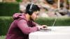 Student using a laptop outdoors on campus 
