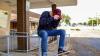  Young person sitting on rail next to building